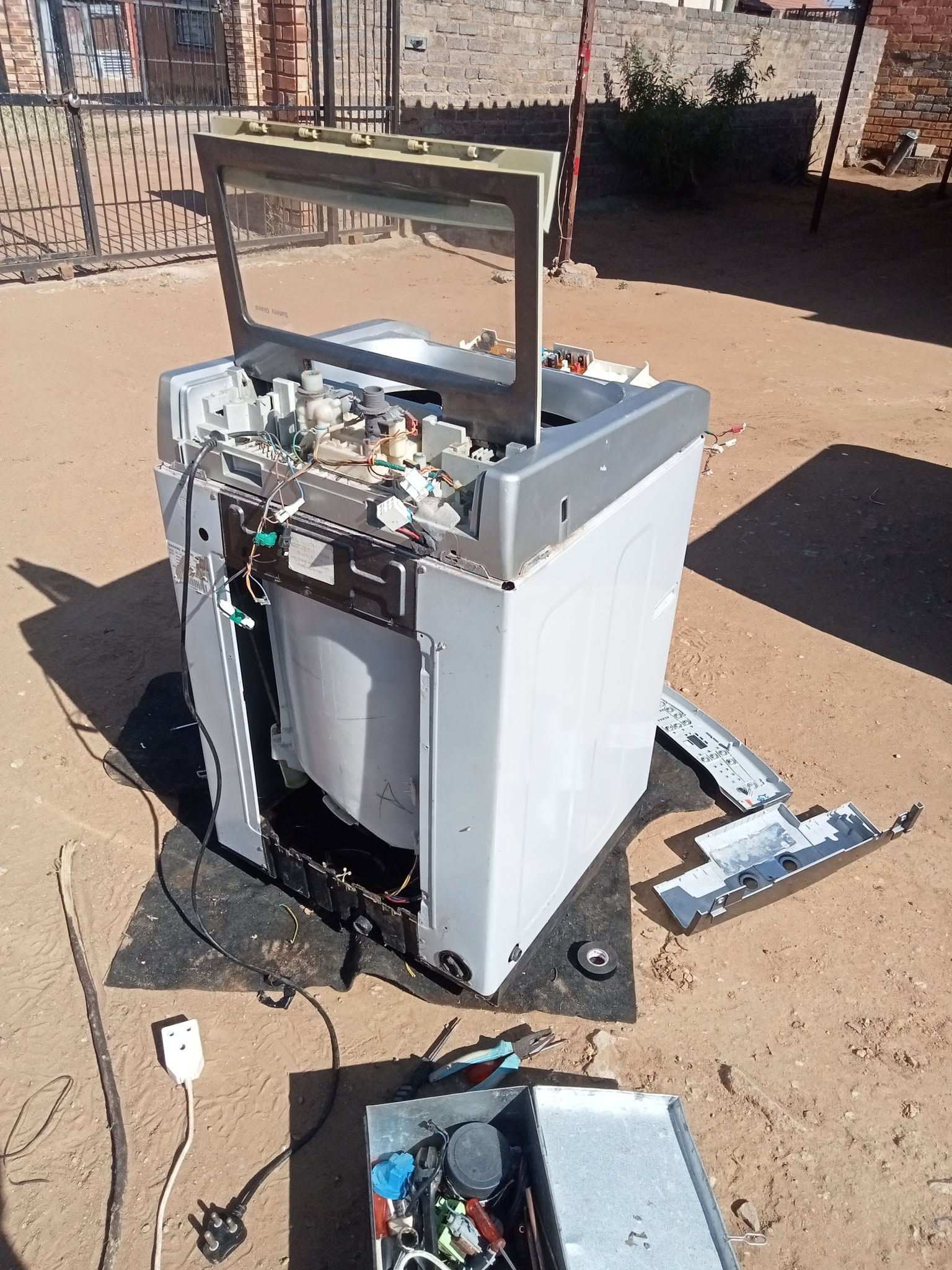 Technician repairing a top loader washing machine on site